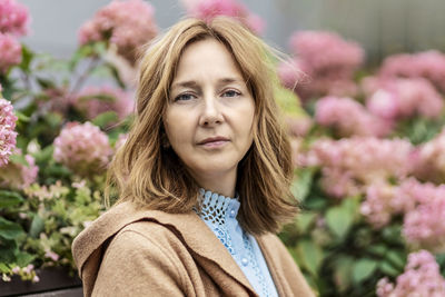 Portrait of young woman standing against plants