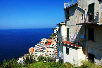 Buildings at manarola sea against clear blue sky