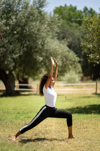 Full length of young woman practicing yoga in warrior position at park