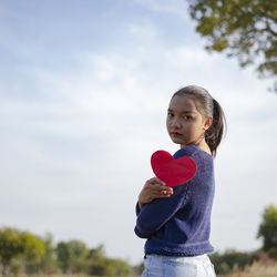 Portrait of a girl holding camera against sky