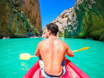 Shirtless man swimming in sea against mountain