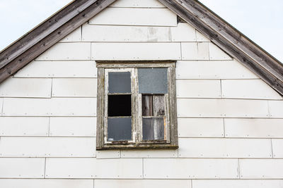 Broken windows of an old, abandoned house with asbestos wall tiles
