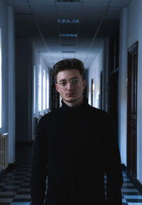 Portrait of young man standing in corridor