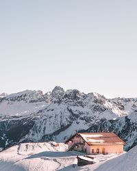 Houses on snowcapped mountain against clear sky