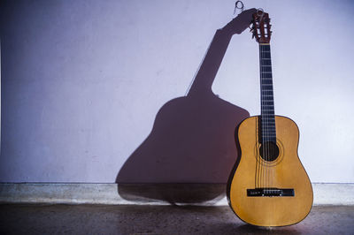 Acoustic guitar on floor against wall at home