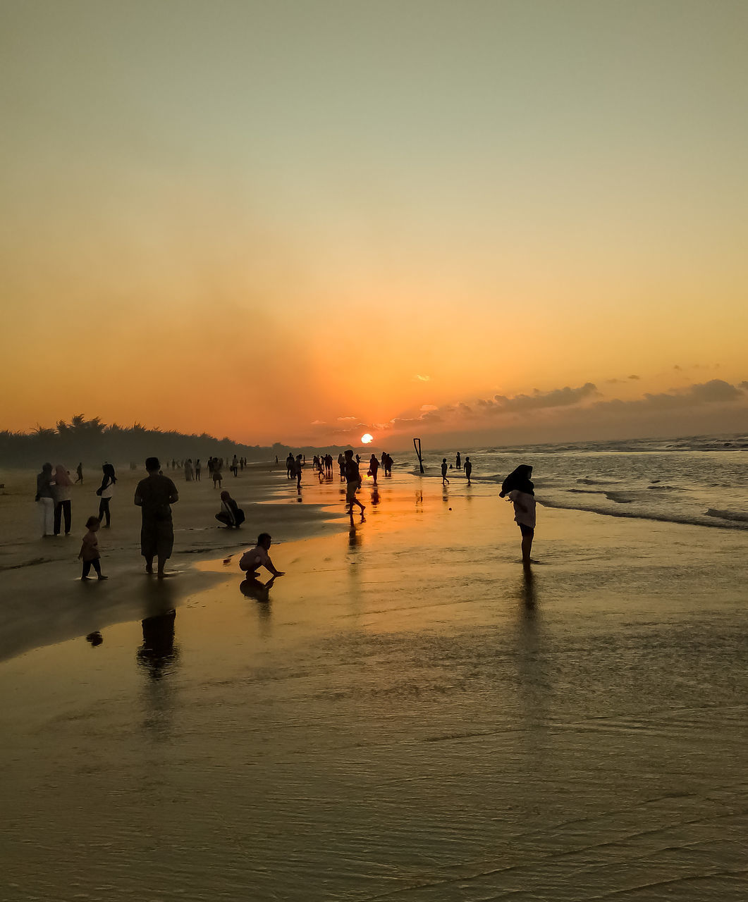 water, sunset, sky, sea, beach, land, group of people, nature, horizon, body of water, beauty in nature, ocean, large group of people, scenics - nature, silhouette, shore, crowd, coast, dusk, wave, orange color, reflection, men, leisure activity, trip, vacation, evening, holiday, sand, lifestyles, sun, outdoors, women, travel destinations, travel, adult, sports, sunlight, tranquility, environment, walking, enjoyment, motion, person, idyllic