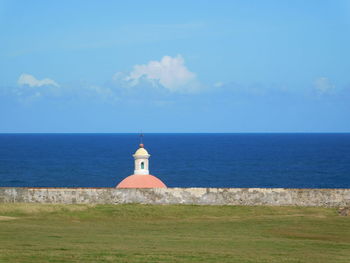 Lighthouse by sea against sky