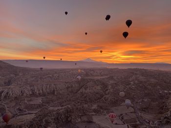 Hot air balloons flying over land during sunset