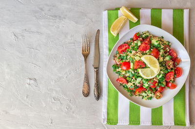 Tabbouleh salad on a dish on light gray concrete background. lebanese cuisine..