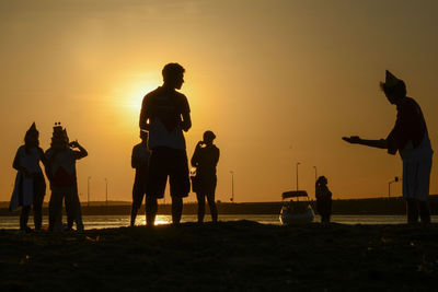 Silhouette people on beach at sunset