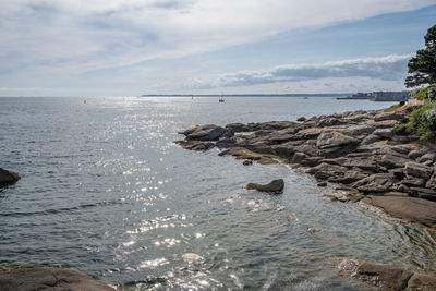 Scenic view of sea with rocky coastline against sky