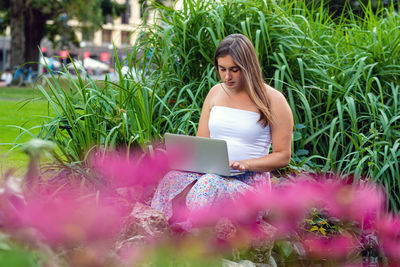 Young woman using laptop sitting at park