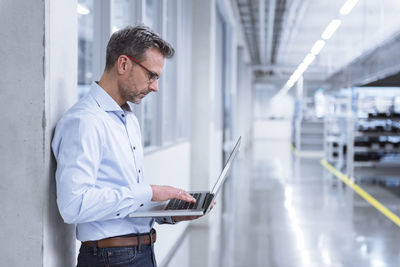 Manager on shop floor of factory using laptop