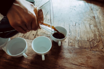 High angle view of hand holding drink on table