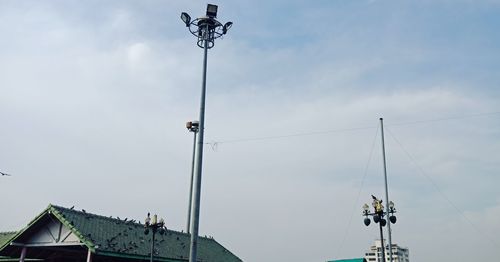 Low angle view of street light by building against sky