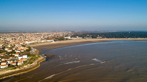 High angle view of townscape by sea against clear sky