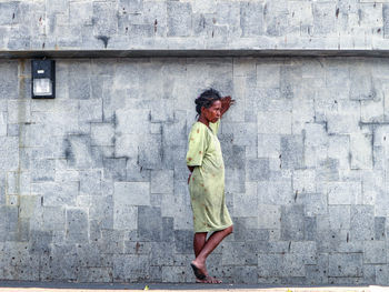 Full length side view of woman walking against wall