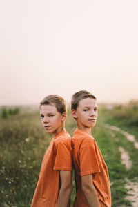 Funny twin brother boys playing outdoors on field at sunset.