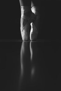 Low section of ballerina balancing on toe against black background