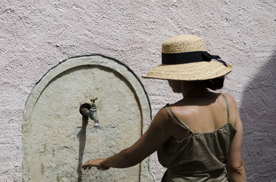 Rear view of woman wearing hat against wall