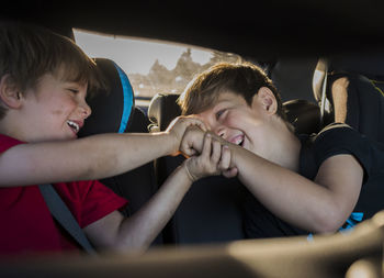 Cheerful brothers playing while travelling in car