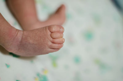 Low section of newborn baby relaxing on bed