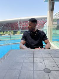 Portrait of young man standing against swimming pool