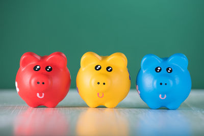 Close-up of piggy banks on table against wall