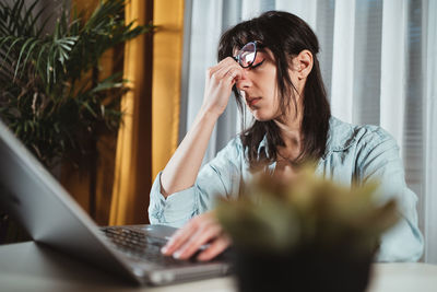 Young woman using phone while sitting on table