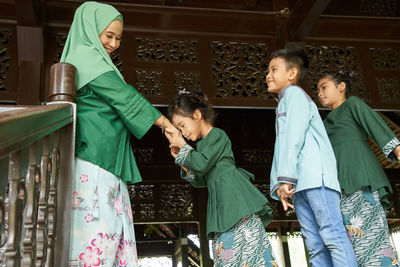Daughter and son standing in a row greeting mother ask forgiveness during ramadan festival 