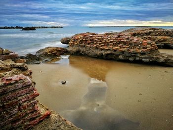 Rocks by sea against sky