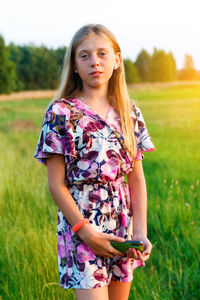 Portrait of teenage girl poses and holding smart phone. front view of charming teen girl in summer 