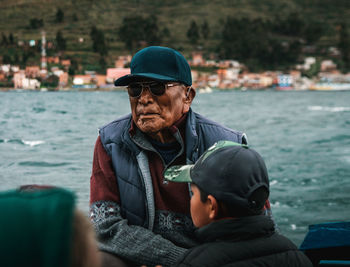 Man looking at camera while sitting by sea