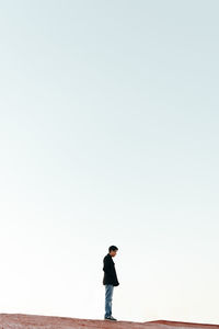 Full length of man standing on rock against clear sky