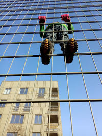 Low angle view of person climbing on fence against sky