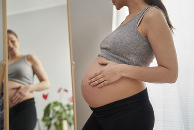 Midsection of pregnant woman looking in mirror
