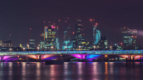 Illuminated bridge over river at night