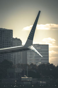 Airplane flying over city against sky