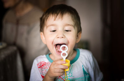 Playful boy holding bubble wand at home