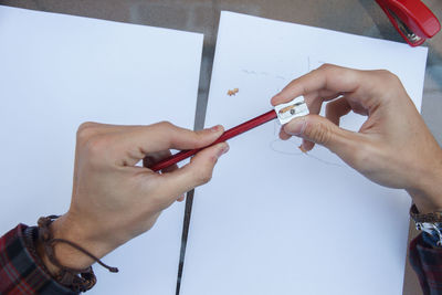 Cropped hands of woman sharpening pencil