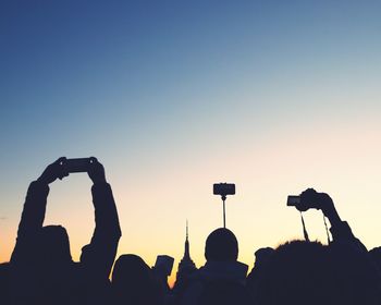 Silhouette people photographing against sky