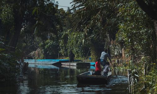 Rear view of man standing on boat in river