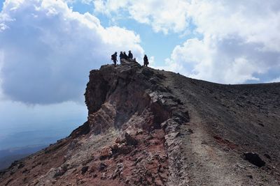 Low angle view of people on rock against sky