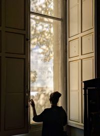 Rear view of man looking through window