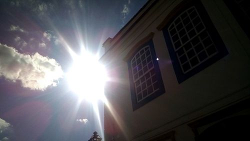 Low angle view of sun shining through clouds