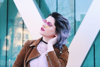 Young woman wearing sunglasses against glass window