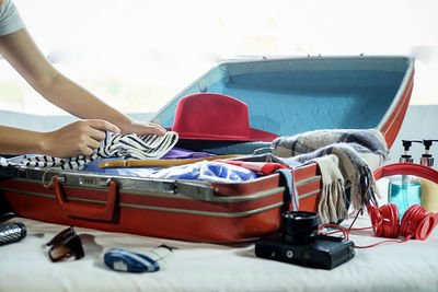 Cropped hands of woman packing suitcase on bed at home