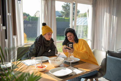 A couple is sitting at the dining table in winter clothes at home, it is cold, they are freezing