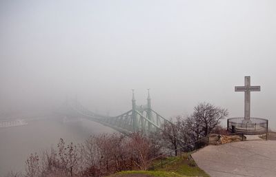 Bridge over river in foggy weather against sky