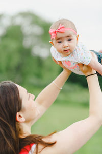 Side view of mother carrying daughter at park